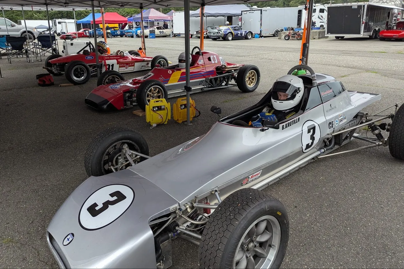 Bill Krutilla strapped into the number 3 car in the paddock, other Formula Fords lined up beside him